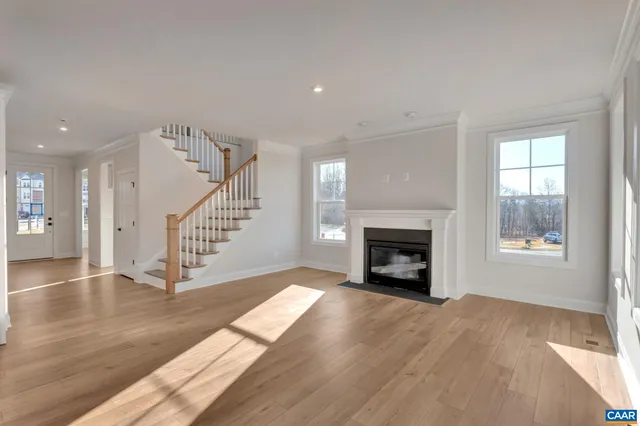 a view of an empty room with wooden floor fireplace and a window