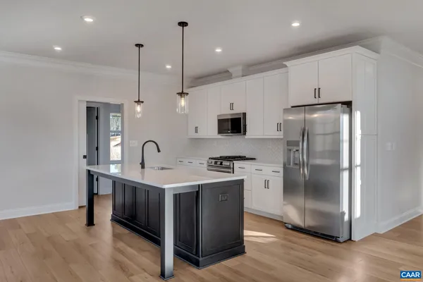 a kitchen with stainless steel appliances granite countertop a refrigerator a sink a stove and a wooden floors