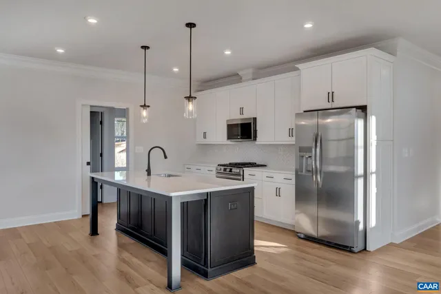 a kitchen with stainless steel appliances granite countertop a refrigerator a sink a stove and a wooden floors