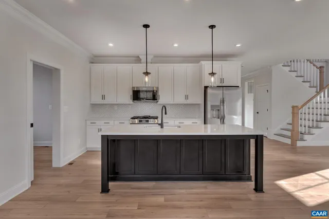 a kitchen with stainless steel appliances granite countertop a sink a stove and a wooden floor