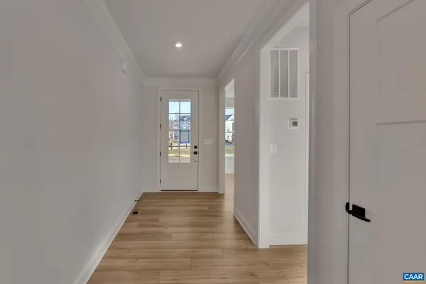 a view of a hallway with wooden floor and a bathroom