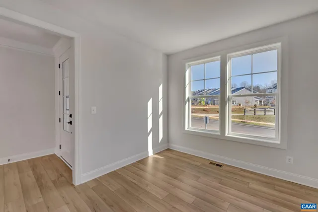 a view of an empty room with a window and wooden floor