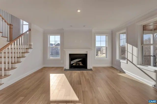 a view of an empty room with wooden floor fireplace and a window