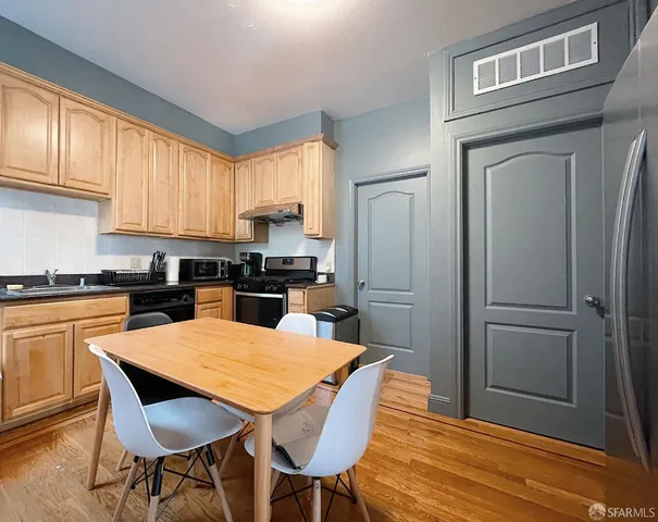 a kitchen with stainless steel appliances wooden floor dining table and chairs