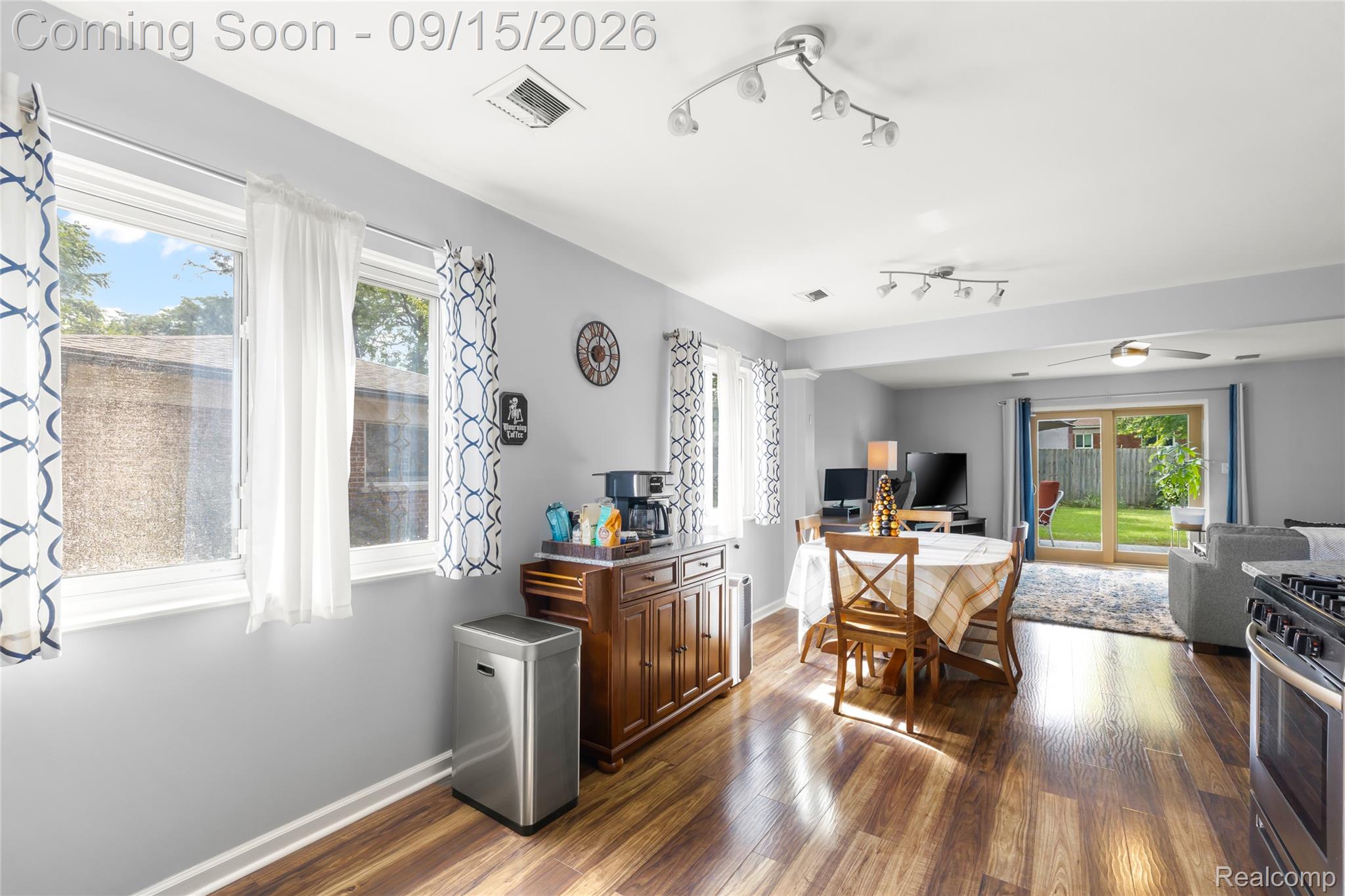Expansive wood-finish flooring, track lighting, and a sliding glass door providing access to the exterior