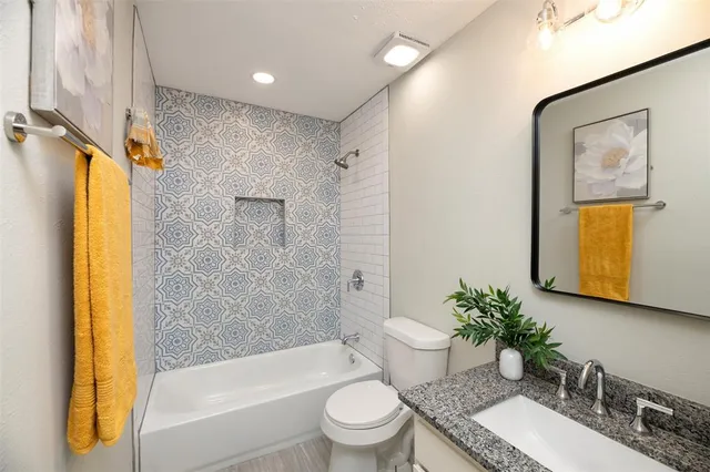 a bathroom with a granite countertop sink toilet and shower