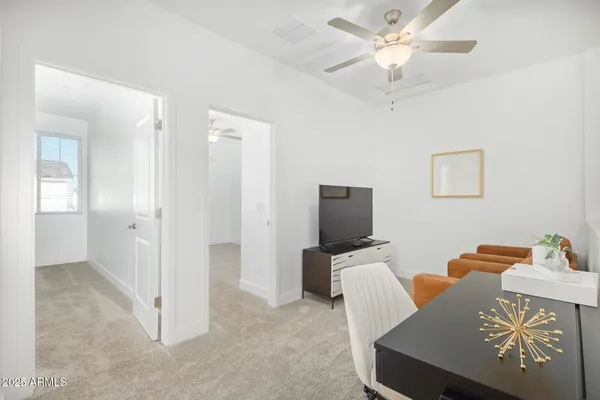 a reading room with furniture and a chandelier fan