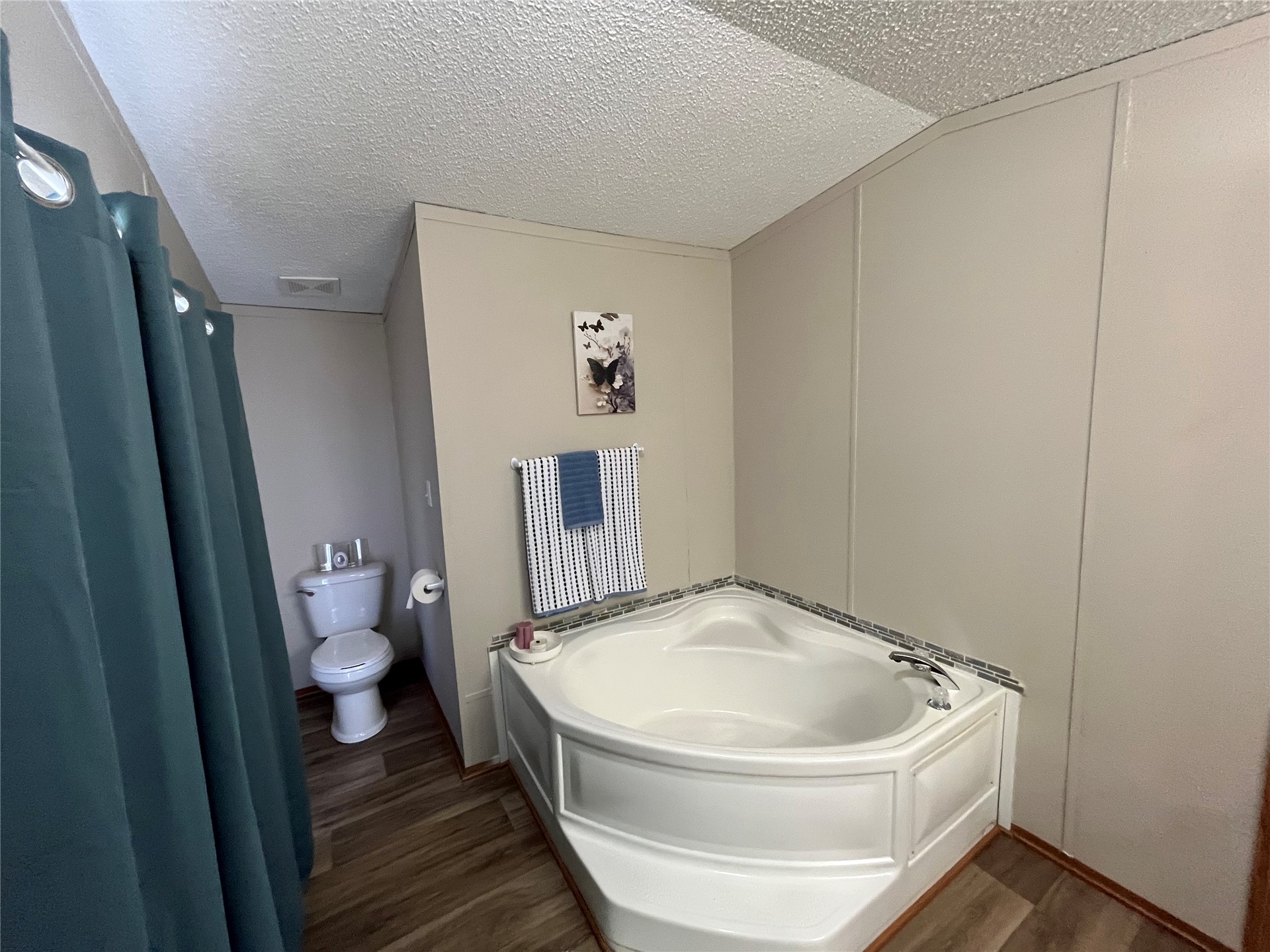 428628 East 1133 Road Porum, OK 74455 - Photo 9 of 16 Corner soaking tub with a tiled surround, paneled walls, and wood-finish flooring