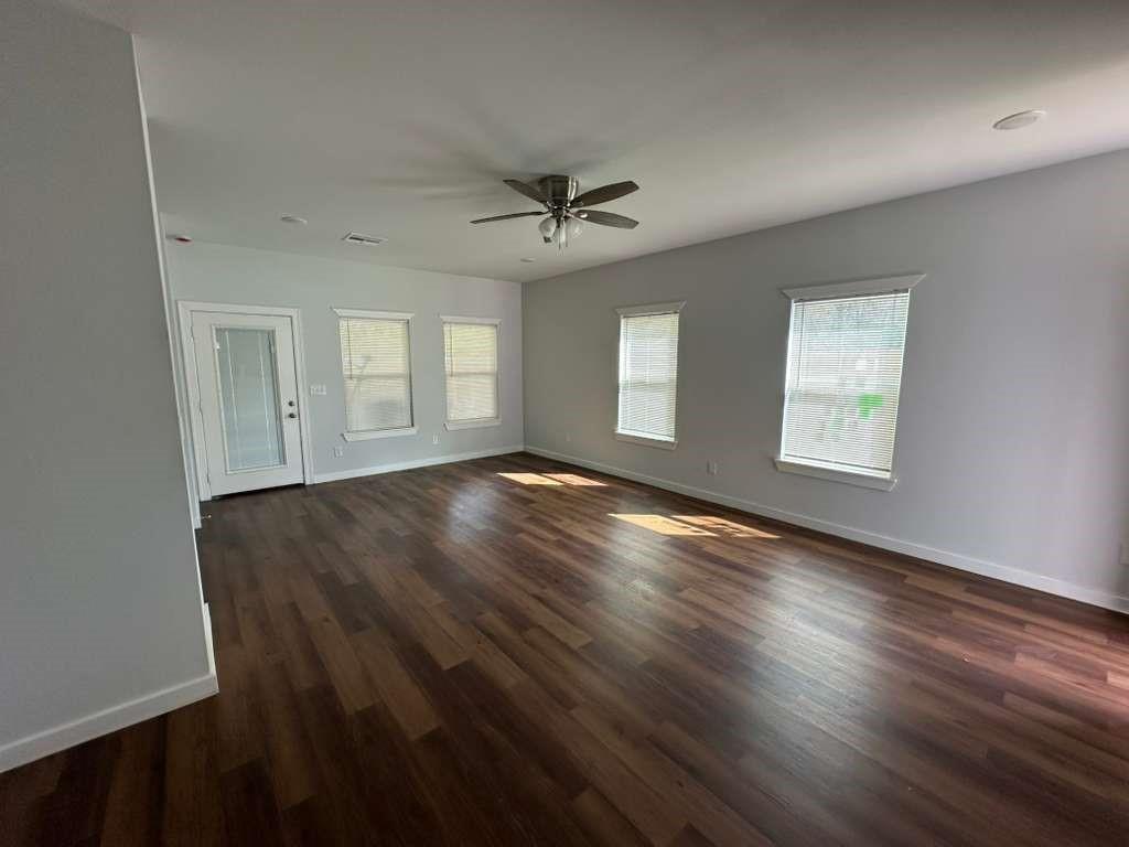 1307 West 33rd Street Tyler, TX 75702 - Photo 2 of 11 an empty room with wooden floor ceiling fan and windows