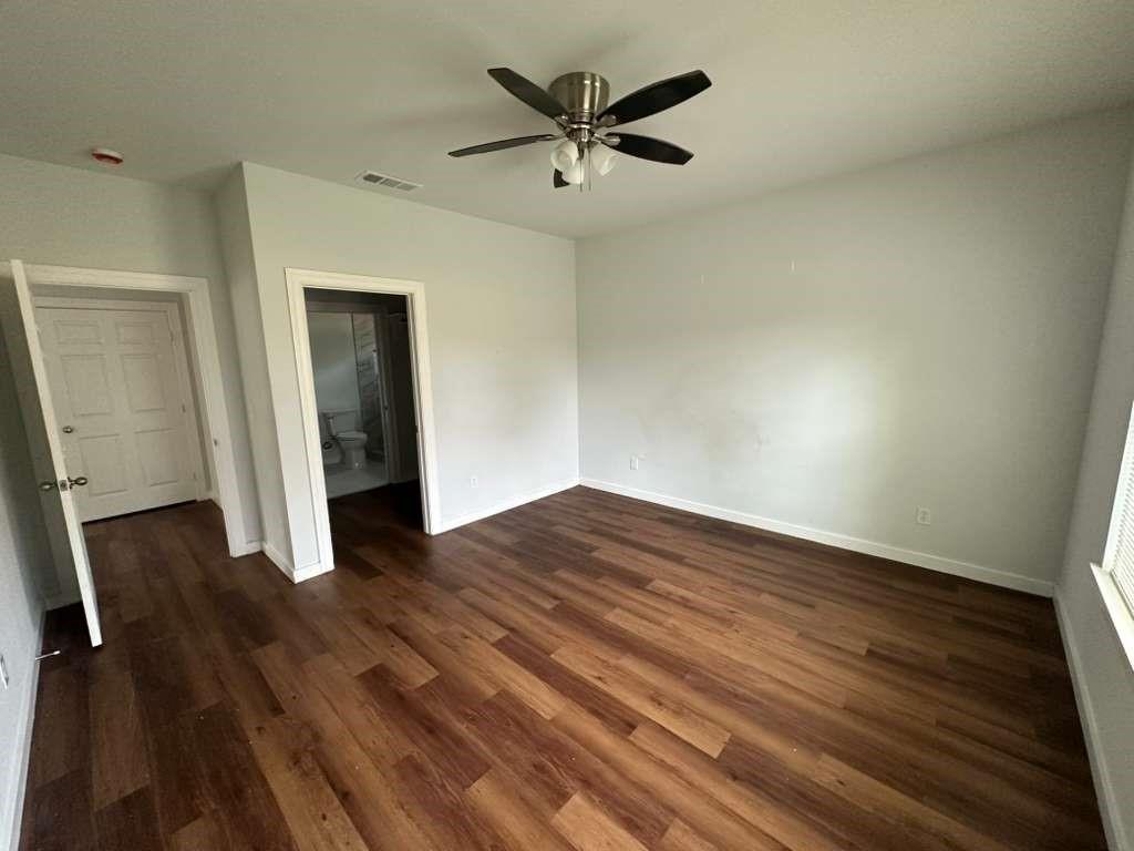 1307 West 33rd Street Tyler, TX 75702 - Photo 4 of 11 an empty room with wooden floor and a ceiling fan