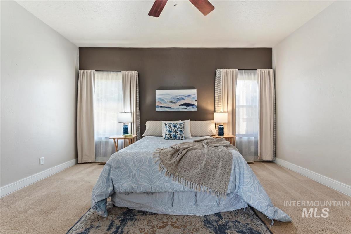 640 Southwest Miner Street Mountain Home, ID 83647 - Photo 18 of 35 Spacious room featuring neutral carpet flooring, a dark accent wall, two windows with drapes, and a ceiling fan