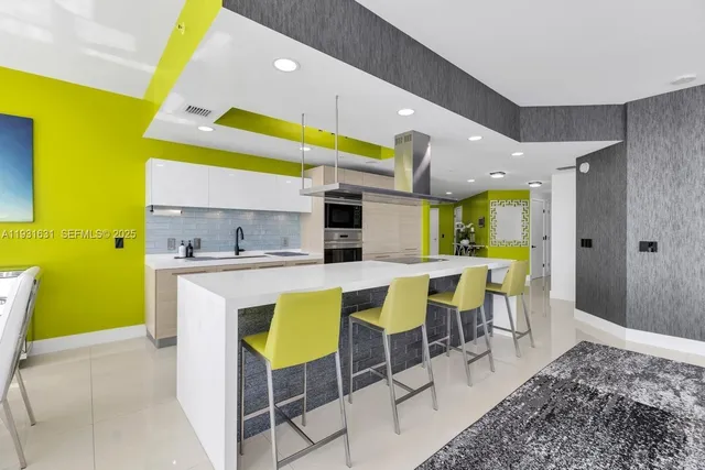 a kitchen with stainless steel appliances kitchen island granite countertop a table chairs and a refrigerator