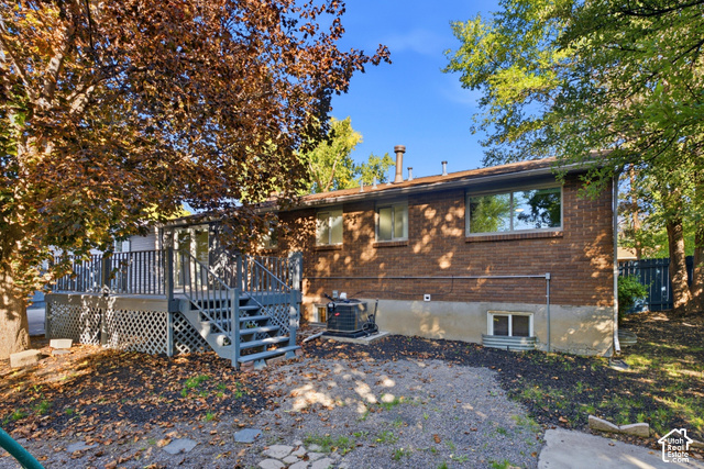8746 Gladiator Way Sandy, UT 84094 - Photo 28 of 36 Expansive rear deck with stairs, brick exterior, and mature trees