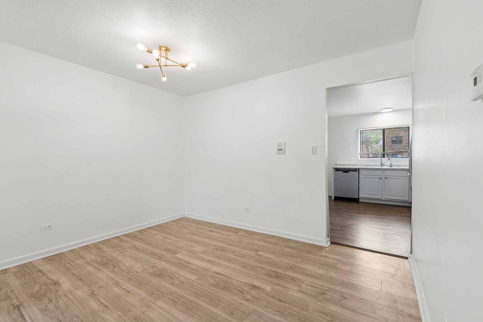 2213 West Nichols Road, Unit B Arlington Heights, IL 60004 - Photo 5 of 23 a view of an empty room with a chandelier fan and wooden floor