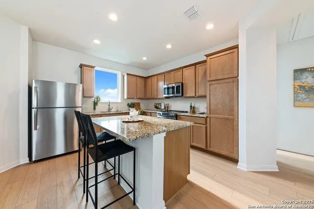 a kitchen with stainless steel appliances granite countertop a refrigerator a sink a stove a microwave and a refrigerator