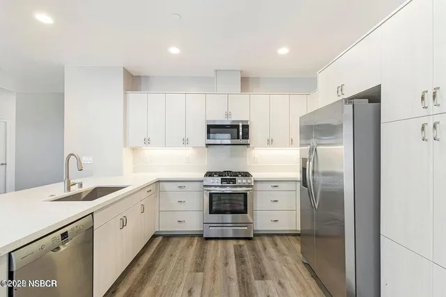 a kitchen with a sink stainless steel appliances and white cabinets