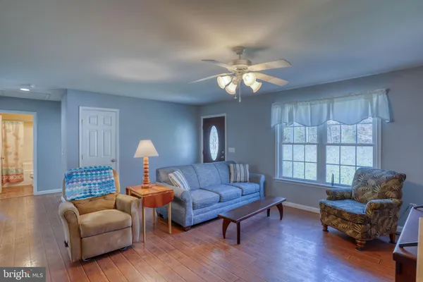 a living room with furniture a ceiling fan a lamp and a window