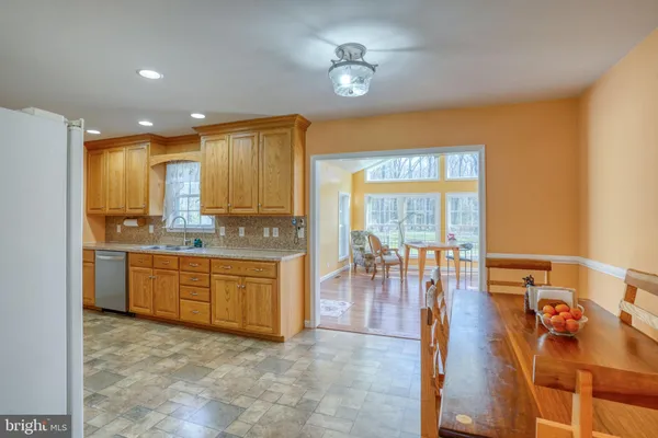 a large kitchen with kitchen island a large window a sink stainless steel appliances and cabinets