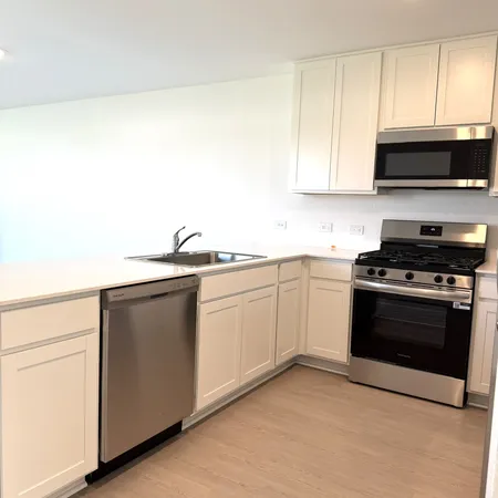 a kitchen with stainless steel appliances a sink dishwasher a stove and white cabinets