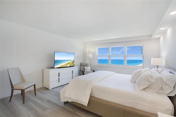 a spacious bedroom with a bed a flat screen tv and windows
