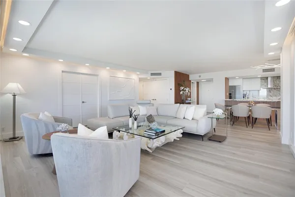 a living room with couches and a dining table with kitchen view