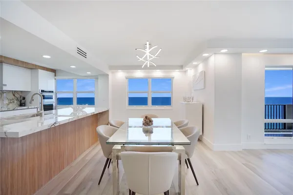 a kitchen with stainless steel appliances kitchen island granite countertop a table chairs in it and wooden floors