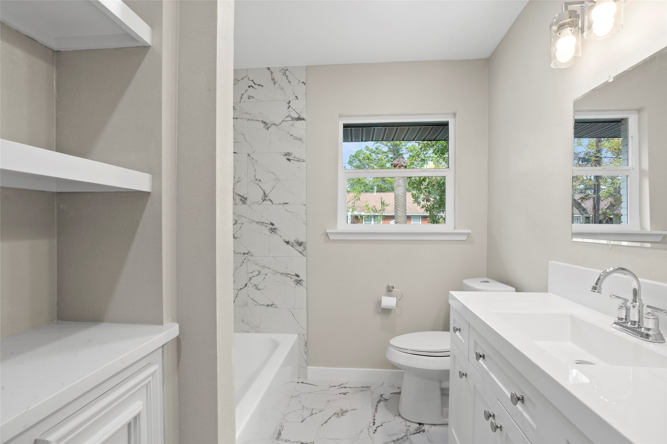 10127 Tolman Street Houston, TX 77034 - Photo 21 of 27 This community bathroom is characterized by a bright, modern aesthetic, utilizing high-contrast materials and crisp white finishes to create a clean and functional space.