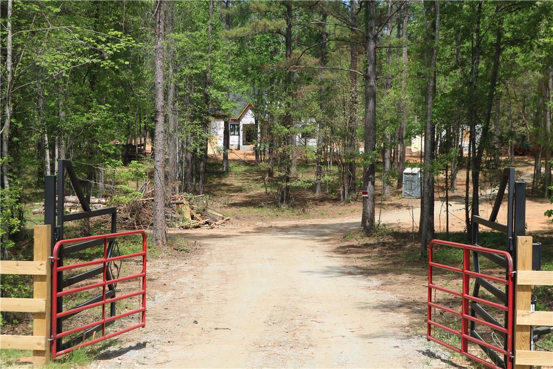 220 Mill Pine Road Liberty, SC 29657 - Photo 7 of 11 A gated entrance leads to a secluded building site nestled among lush trees, offering a private retreat!