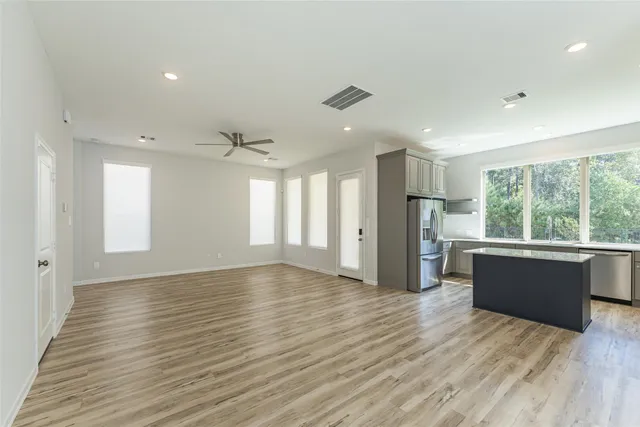 a view of empty room with wooden floor and fan