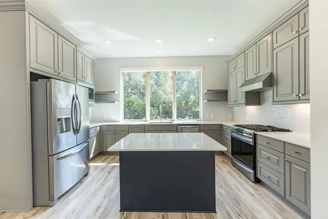 a large kitchen with granite countertop a stove top oven a sink and dishwasher a refrigerator with wooden floor