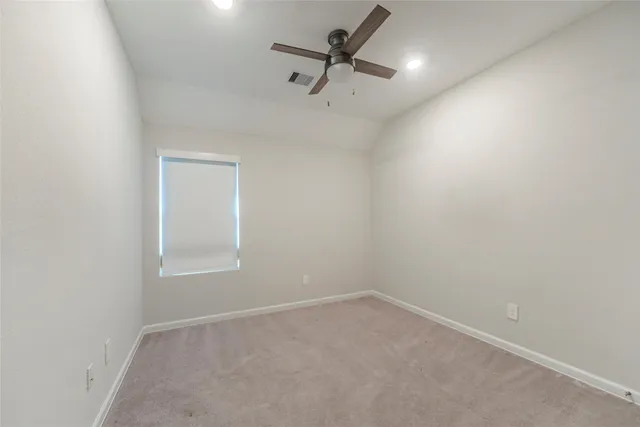 an empty room with a ceiling fan and window