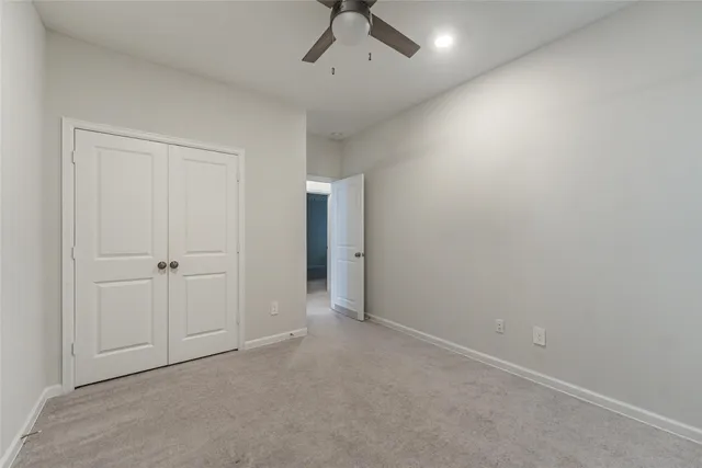 an empty room with a ceiling fan and carpet