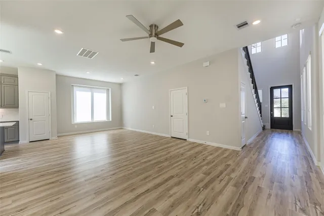 an empty room with wooden floor and a ceiling fan