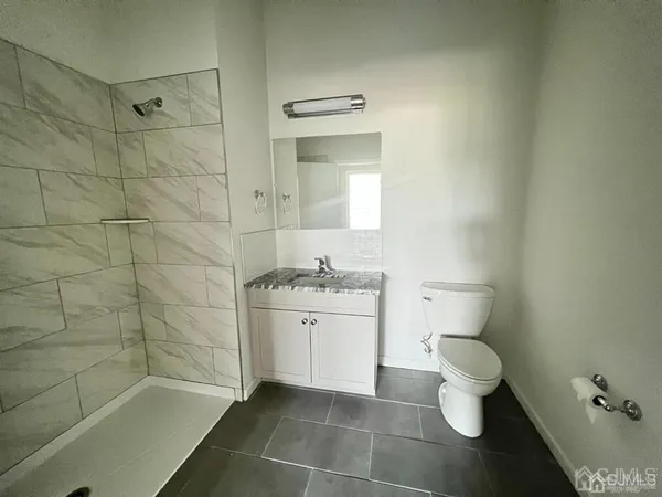 a bathroom with a granite countertop sink a toilet and shower