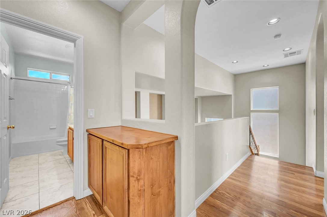 977 Sparkling Light Street Henderson, NV 89052 - Photo 39 of 75 This bright hallway connects a private bathroom with elegant hardwood floors and ample natural light.