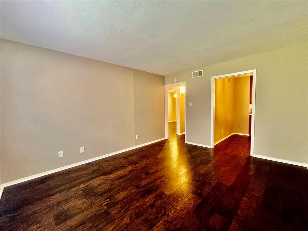 1107 North Locust Street, Unit 4 Denton, TX 76201 - Photo 2 of 8 Spacious living room featuring dark wood-style flooring and neutral walls.