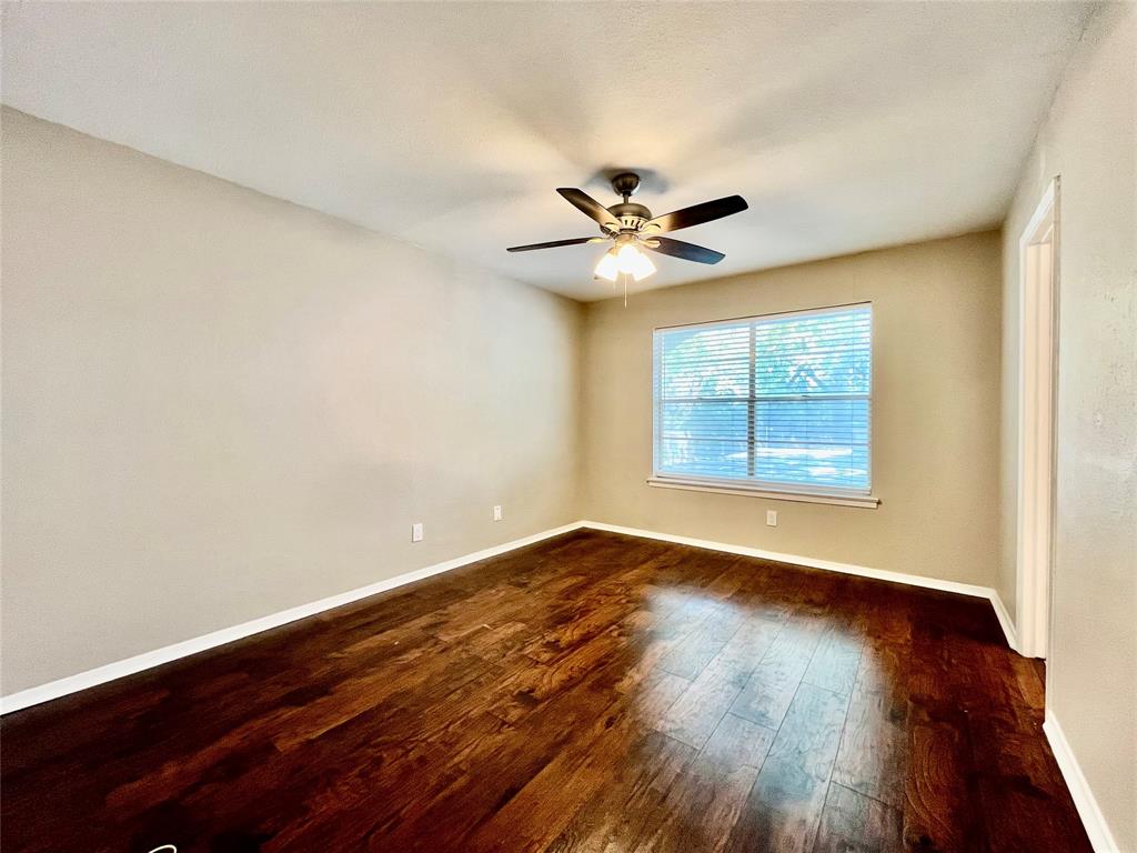 1107 North Locust Street, Unit 4 Denton, TX 76201 - Photo 7 of 8 Primary bedroom with a ceiling fan, large window, and continued wood-style floors.