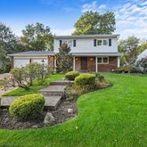a front view of a house with a yard and potted plants