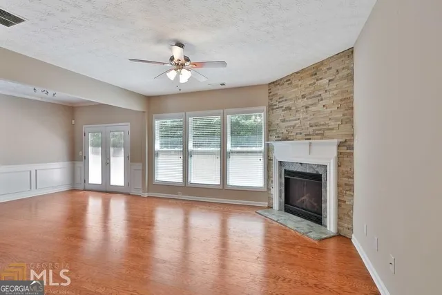 a view of an empty room with wooden floor and a fireplace