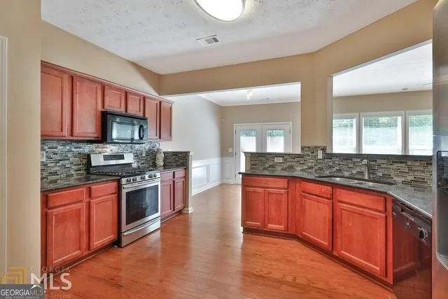 a large kitchen with stainless steel appliances granite countertop a stove and a sink