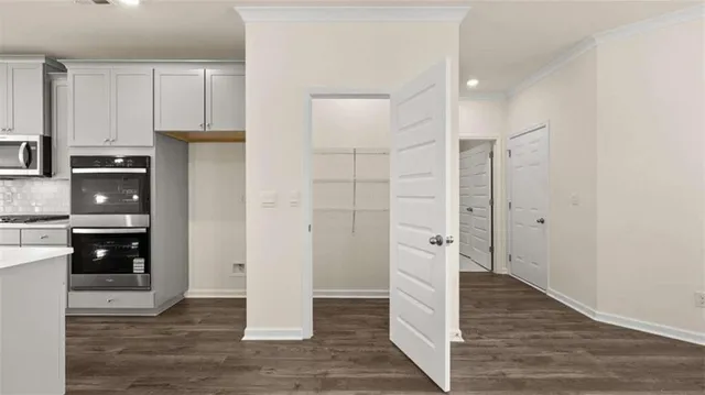 a view of an empty room with wooden floor and a chandelier