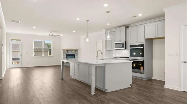 a large kitchen with stainless steel appliances kitchen island a large counter top and wooden floors
