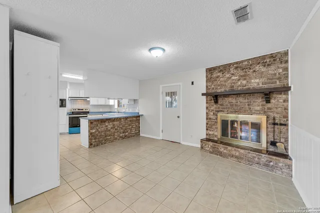 a living room with stainless steel appliances kitchen island granite countertop furniture and a fireplace