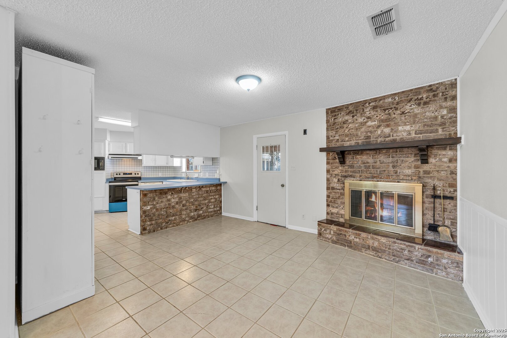 a living room with stainless steel appliances kitchen island granite countertop furniture and a fireplace