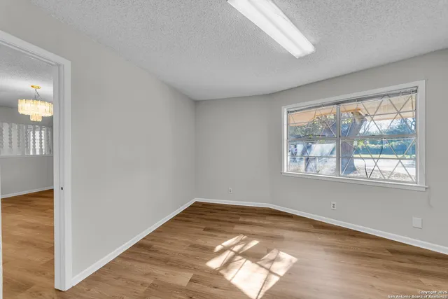 a view of empty room with wooden floor and fan