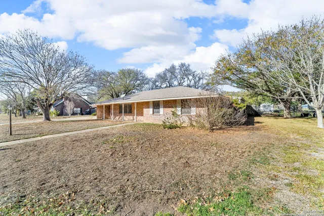 a front view of a house with a yard and large trees