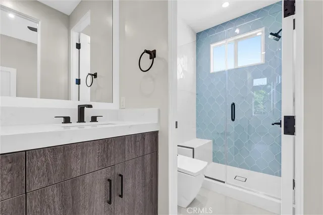 a bathroom with a sink a toilet a mirror and shower