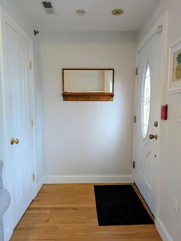 a view of a hallway with wooden floor and cabinet