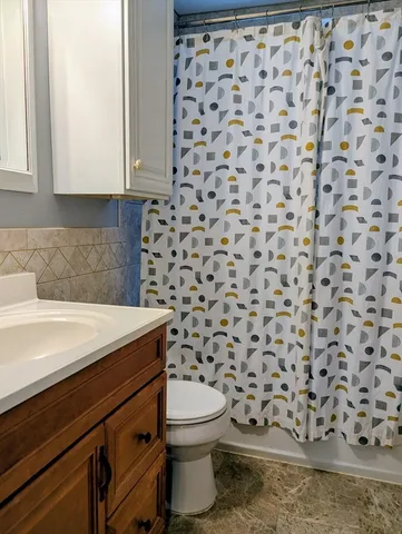 a bathroom with a granite countertop toilet and a sink