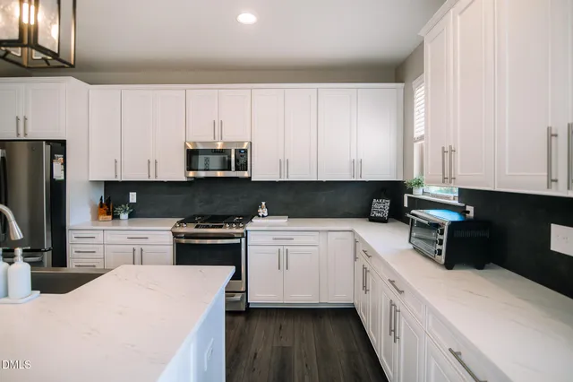 a kitchen with granite countertop white cabinets and stainless steel appliances